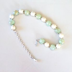 Necklace with pearls and sage green stones having specs of gold.